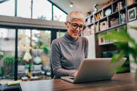 Short-haired older lady with glasses on a laptop